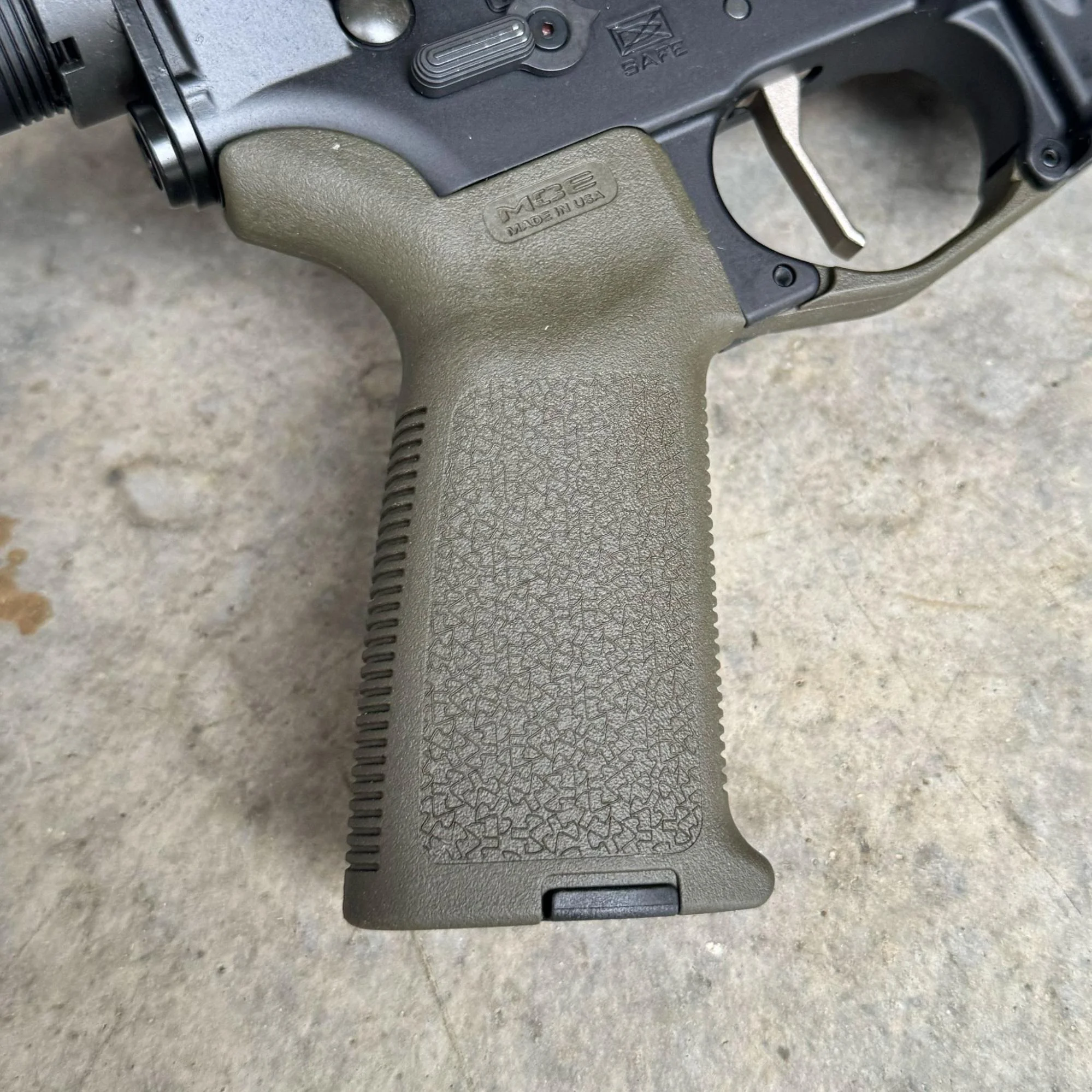 An image of a Magpul MOE+ grip in olive drab green color, fitted on an AR-15 rifle, showcasing how well it complements the rifle's overall appearance