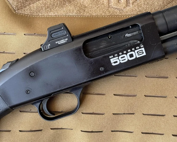 Close-up of Mossberg 590S Compact receiver showing optic-ready Shield RMSc footprint cut and mounted Holosun SCS Carry red dot sight.
