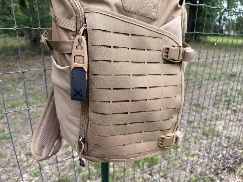 Close-up of the Vertx Siege 25L backpack showing 500D MOLLE webbing on the expandable front pouch, highlighting rugged build and tactical features