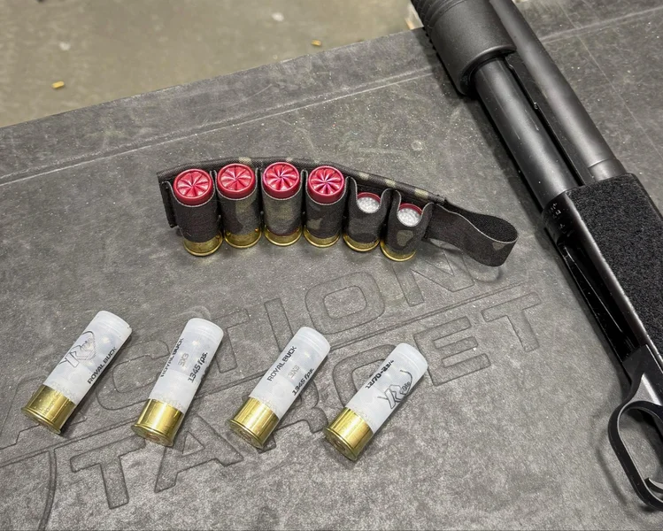 Mossberg 590S Compact shotgun laid on a shooting bench with an assortment of mixed shell types, including mini shells and buckshot, neatly arranged for testing.
