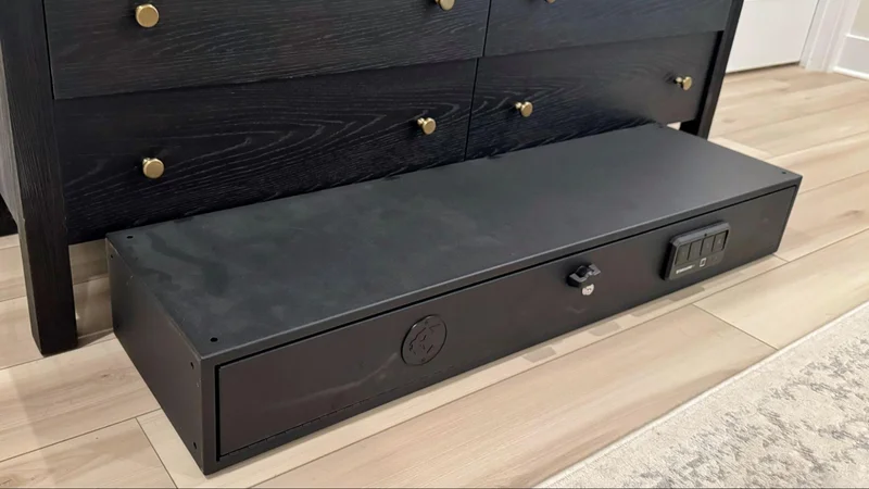  SecureIt Model 47 gun safe positioned horizontally on the floor in front of a dresser, showing near-fit for under-bed or low-clearance storage.