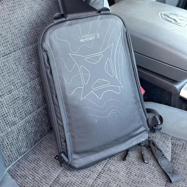 Back side of the VERTX Urban Ghost Sling Bag resting on car seat, showing design pattern
