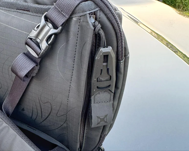 Close-up of the Rapid Access Half-Pull tab on the VERTX sling bag for quick firearm access