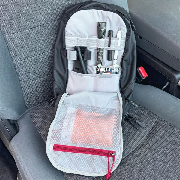 Open sling bag showing organized admin panel with medical supplies, pens, and gear inside elastic loops and mesh pockets