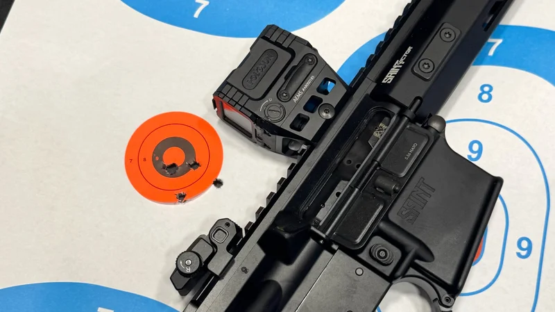 Springfield Saint Victor Pistol with Holosun AEMS optic next to shot grouping on target at 20 yards