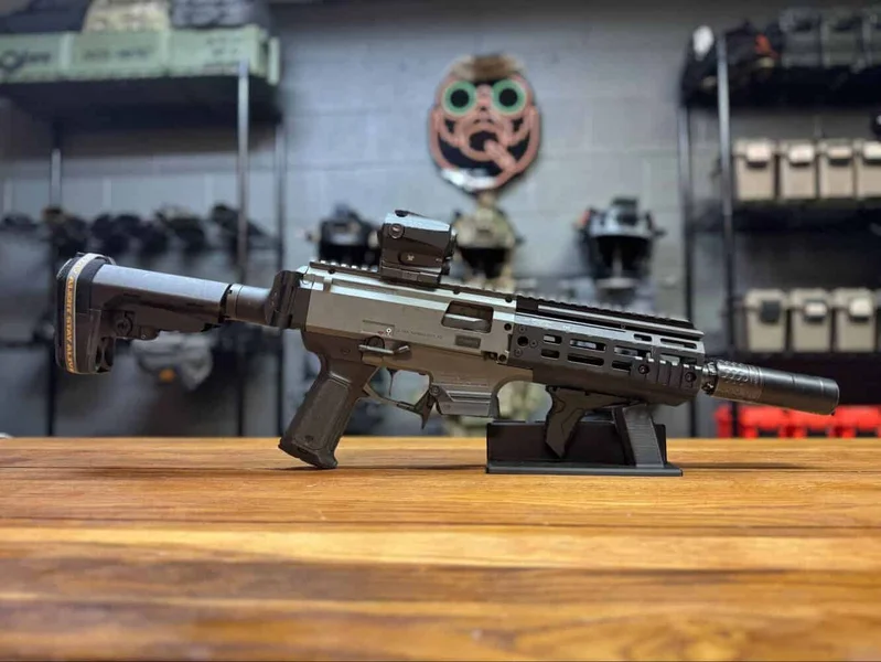 CZ Scorpion Evo 3 resting on a table with optic and suppressor, displayed in a tactical gear room.