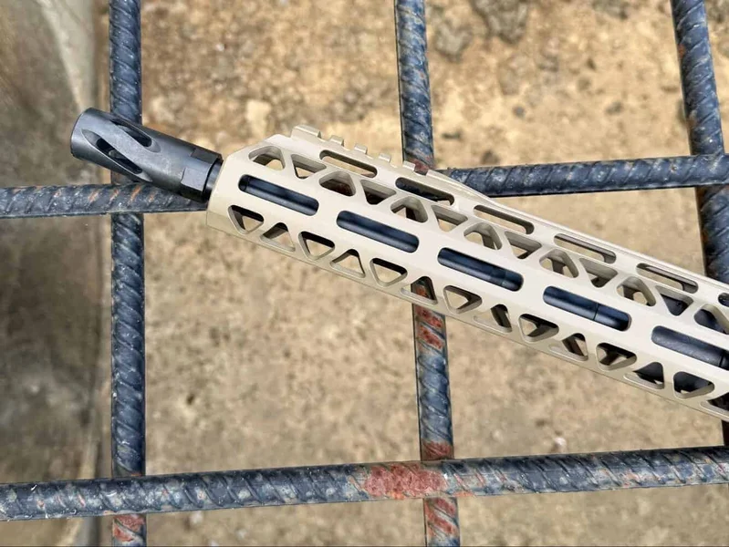 Close-up of FDE handguard and black flash hider on Bear Creek Arsenal BC-15 resting on a metal grate