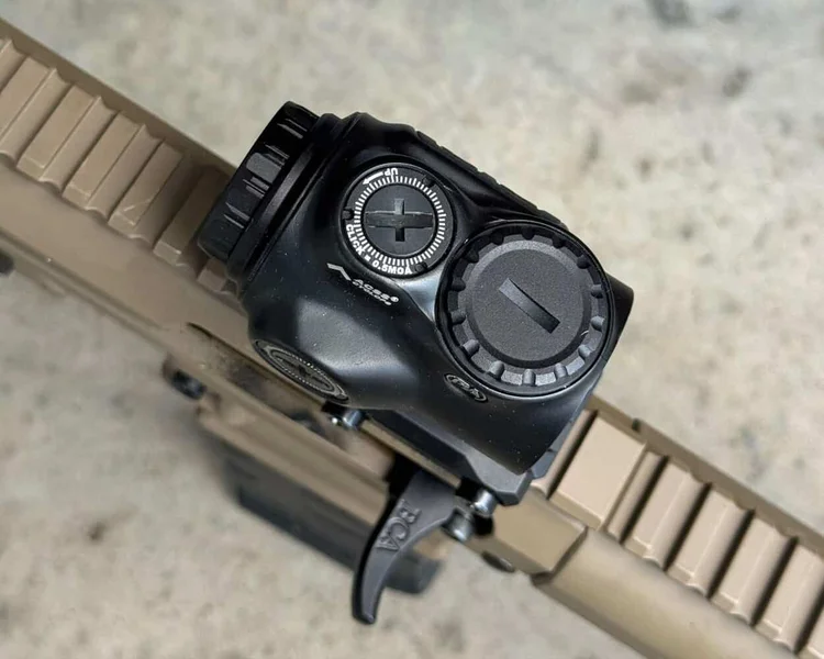 Close-up of GLx 1x optic mounted on flat dark earth (FDE) rifle rail, showing battery cap and controls.