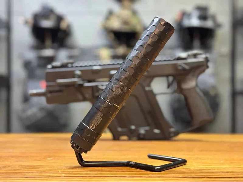 Close-up of Lone Wolf Elimin8r .45 suppressor mounted on a firearm, standing upright on a table.