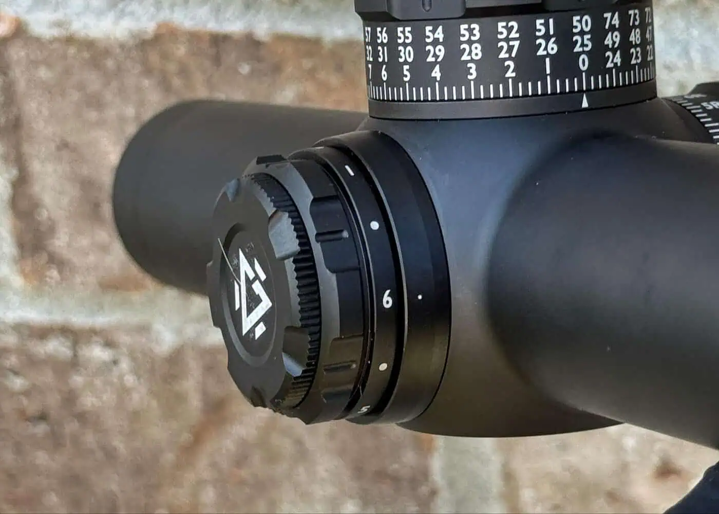 Close-up of the GUNNR Odin LPVO brightness adjustment dial set near maximum, with turret markings visible