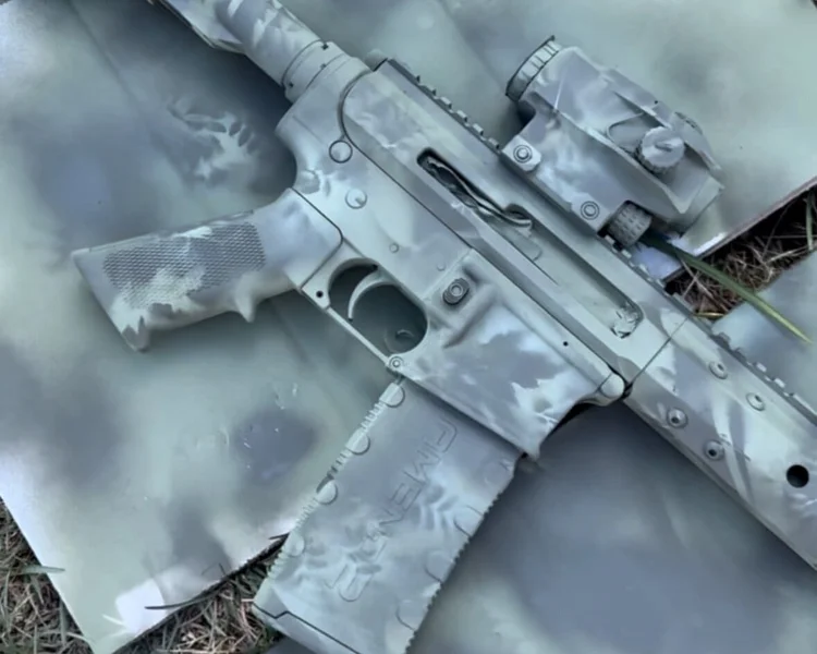 DIY camo-painted Bear Creek Arsenal BC-15 rifle lying on spray-painted cardboard