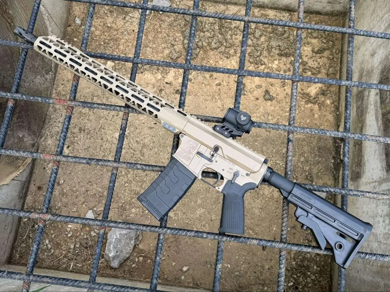 Flat Dark Earth and black Bear Creek Arsenal BC-15 AR-15 rifle with Kustom Kote Cerakote finish resting on a metal grate.