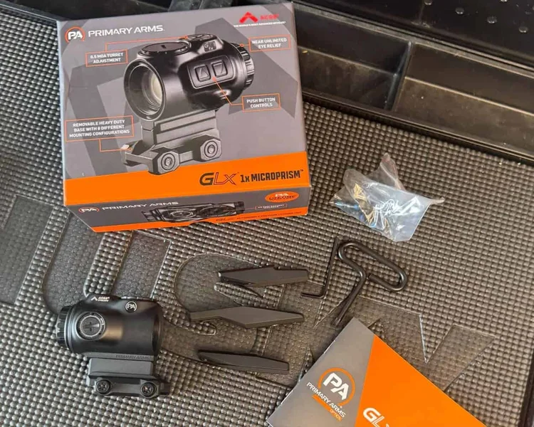 GLx 1x MicroPrism optic and accessories laid out on a mat, including the box, mount, spacers, tools, and user manual.