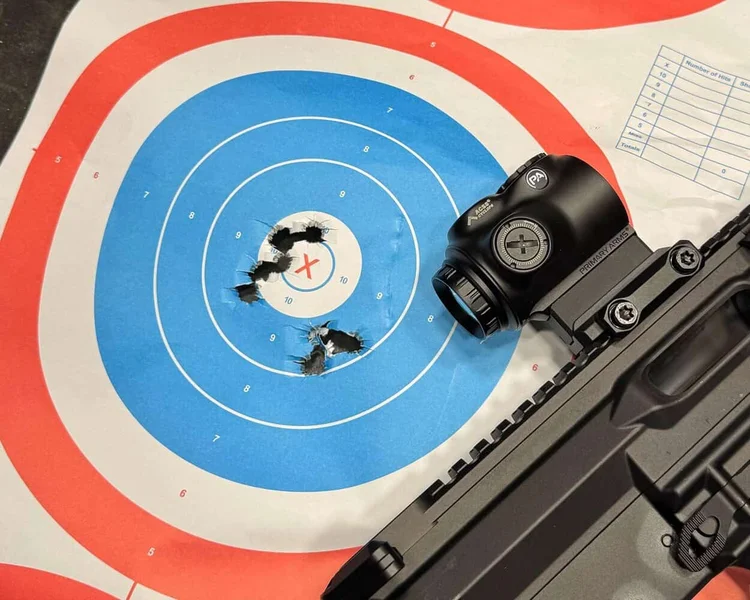 GLx 1x optic mounted on a rifle next to a paper bullseye target showing tight shot grouping near the center.