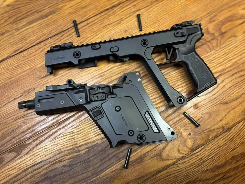 Kriss Vector Gen 3 disassembled into upper and lower sections, with four pins laid out on a wood surface.