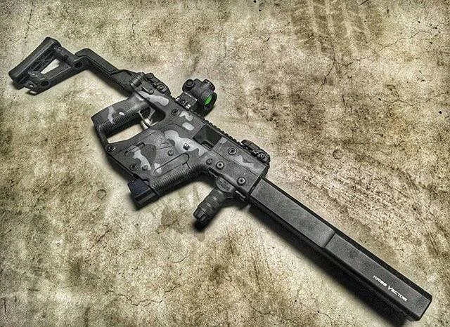 Kriss Vector Gen 3 with suppressor, optic, angled foregrip, and camouflage paint job on a concrete surface.