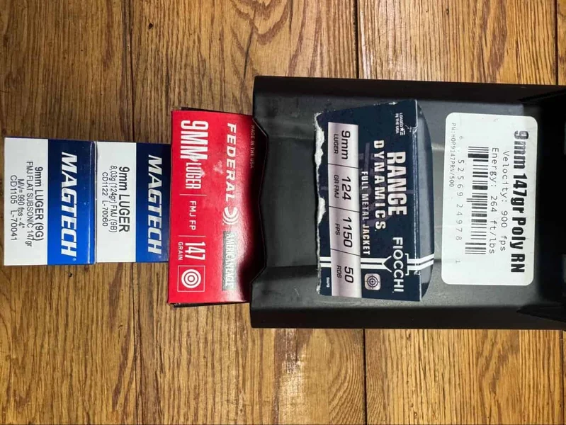 Six boxes of different 9mm ammunition brands including Fiocchi, Magtech, and Federal, shown on wood background.