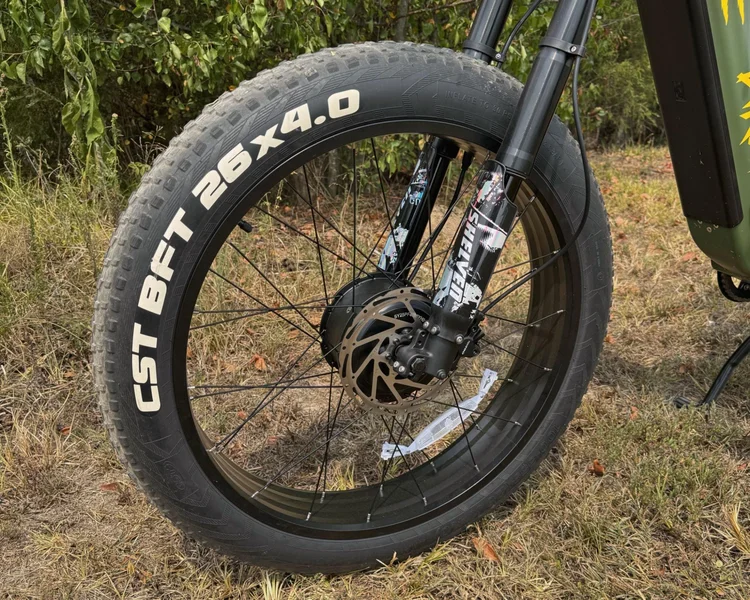 Close-up of CST BFT 26x4.0 fat tire and front suspension fork on Birch Grolar AWD hunting bike, emphasizing off-road durability.