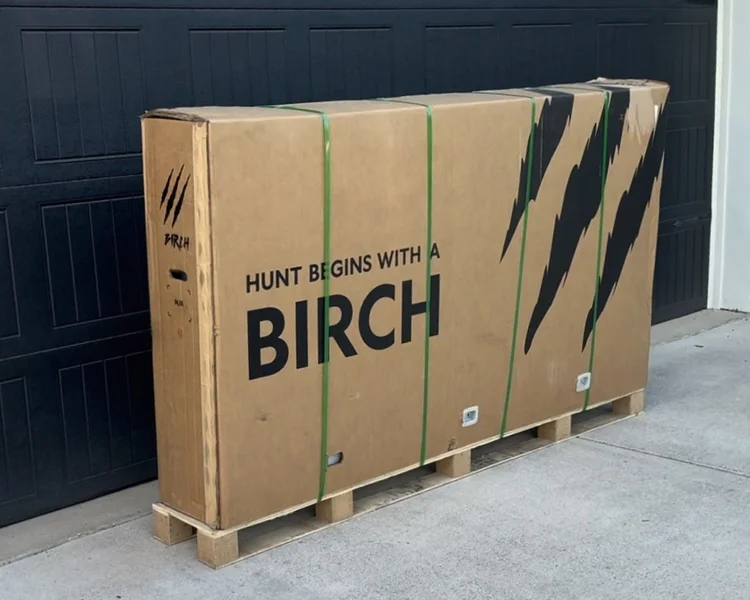 Large Birch Grolar AWD hunting bike shipping box on a pallet, delivered securely in protective packaging in front of a garage.