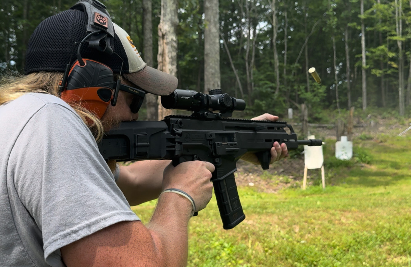 Shooter firing the IWI Carmel rifle at an outdoor range with visible shell ejection mid-air