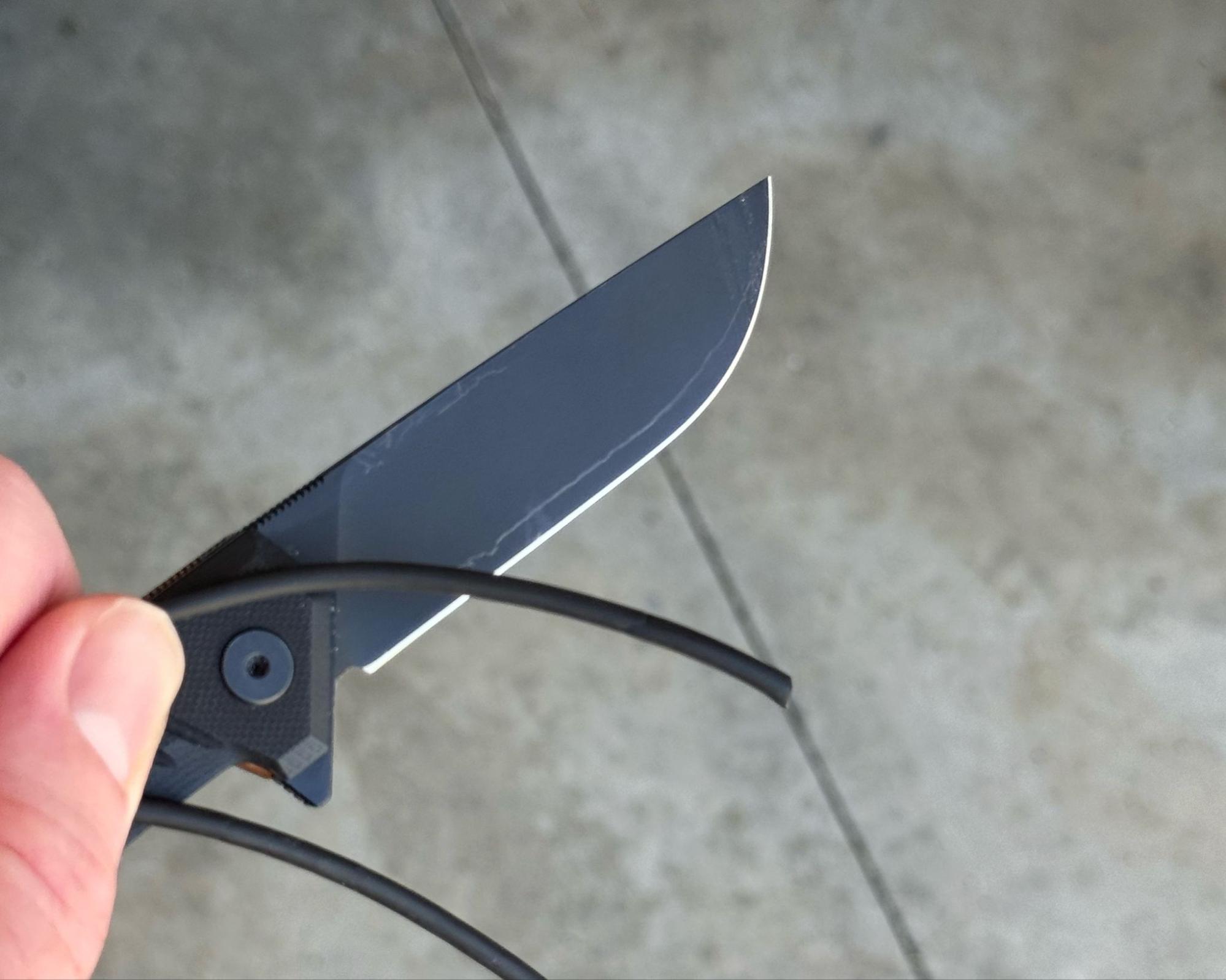 Tekto F1 Alpha EOTECH knife cutting through an old black charging cable