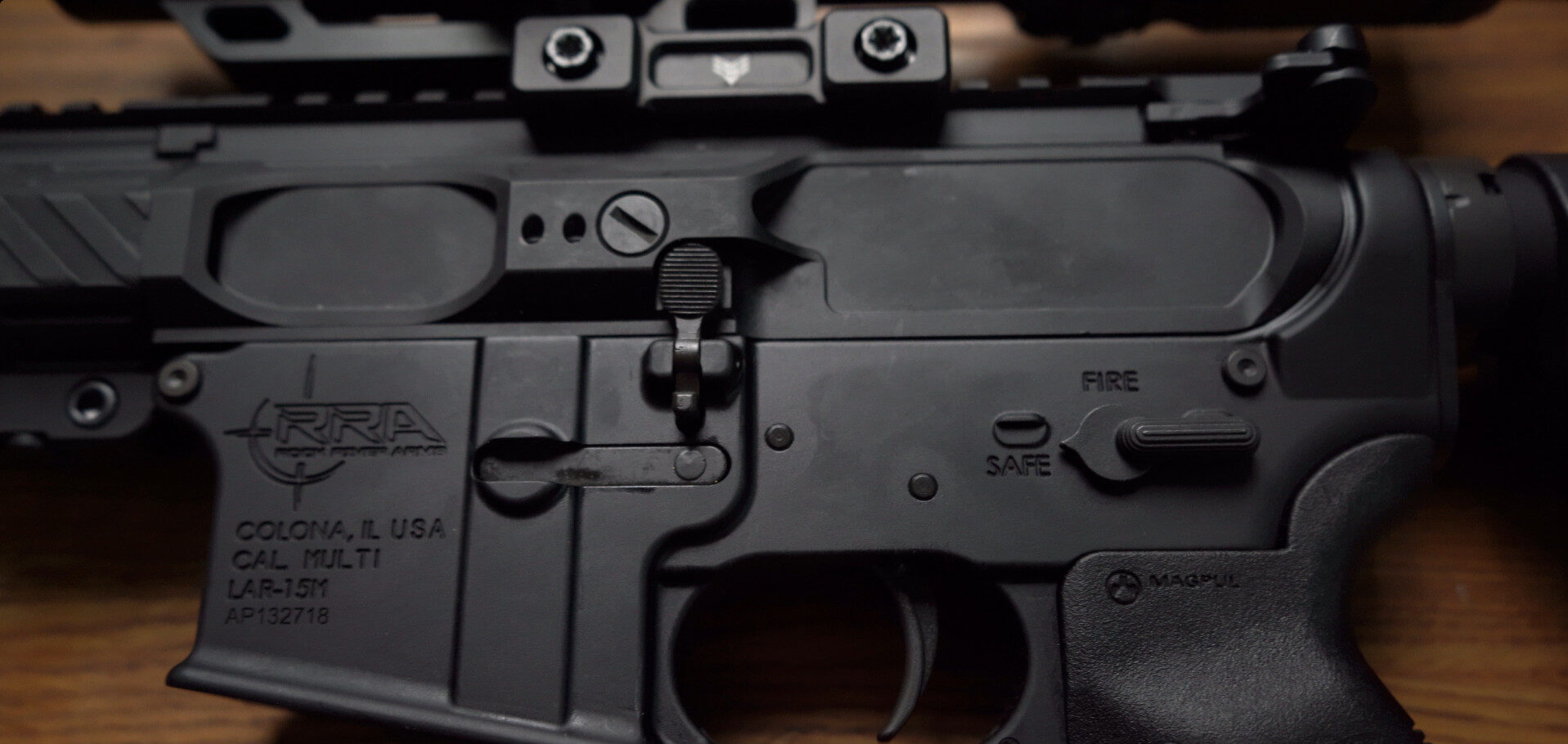 Close-up of Rock River Arms LAR-15M lower receiver showing controls, trigger, and safety markings