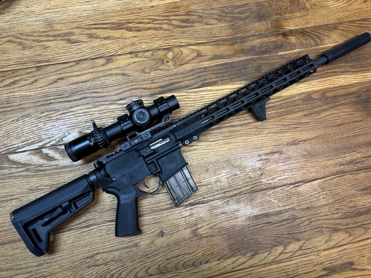 Rock River Arms LAR-15M .17 HMR rifle with scope, magazine, and suppressor shown on wooden surface