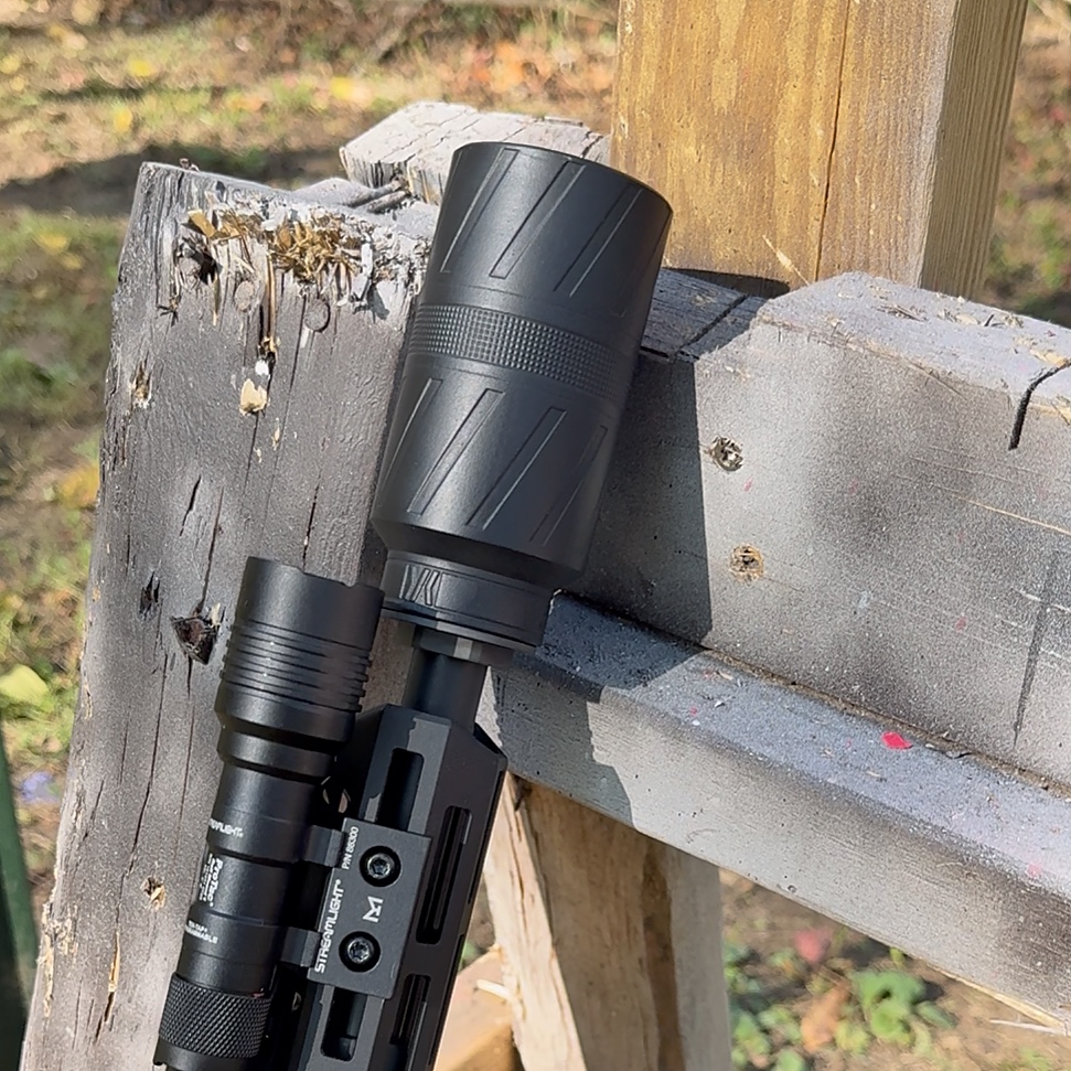 BANISH Speed K suppressor mounted on AR-15 with tactical light, resting against wooden post