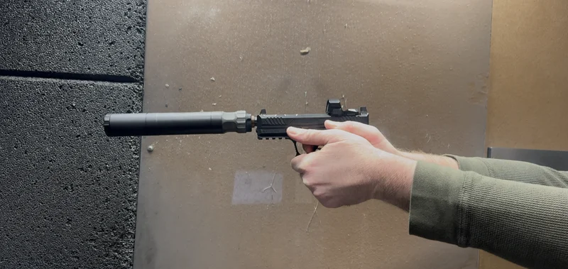 Close-up of BANISH 45 silencer mounted on Strike Arms pistol in shooting position