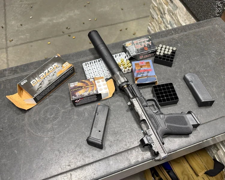 Pistol with BANISH 45 suppressor and ammo setup at indoor shooting range