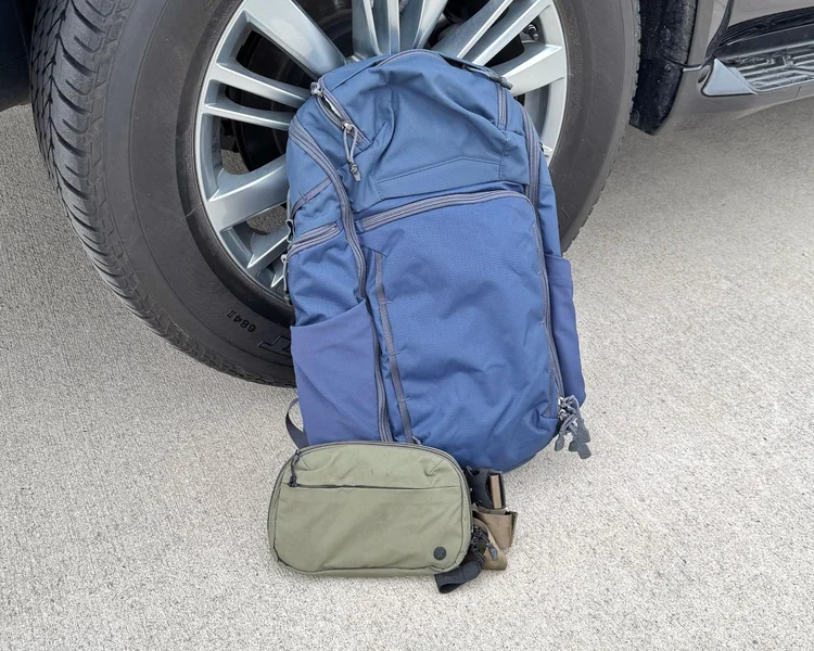 Blue Vertx Gamut 26L backpack and olive green Everyday Fanny Pack 2.1 on concrete