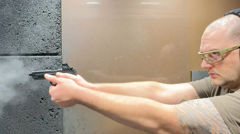 Aiming and firing a suppressed Smith & Wesson M&P22X pistol at an indoor shooting range